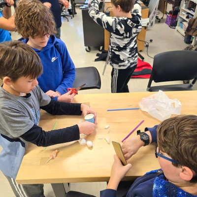 Three students work on project at a table in a classroom 