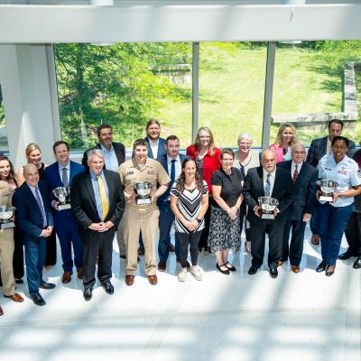 Group of professionals holding awards in front of a widow