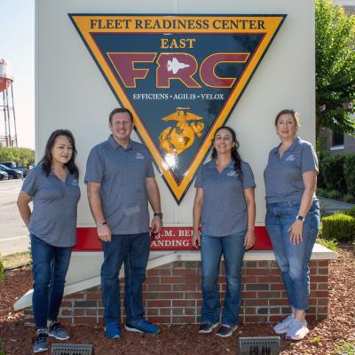 Four adults standing outside in front of FRCE sign