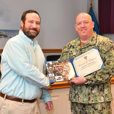 Man in military uniform stands with man in blue shirt 