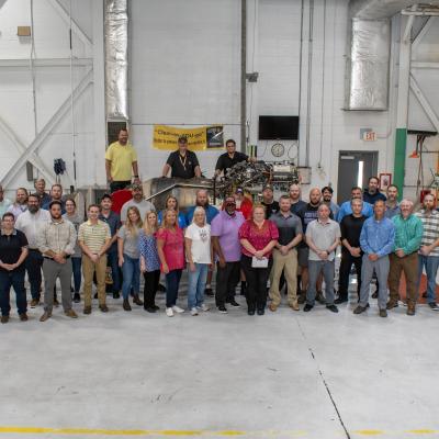 Group of people stand in front of aircraft engine 
