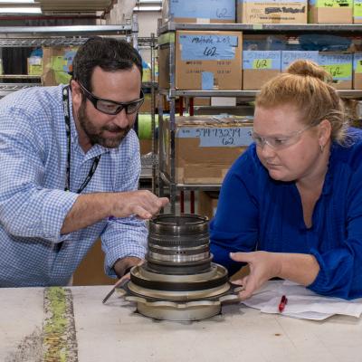 man and woman inspect mechanical part 