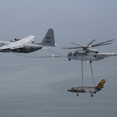 C-130 plane aerial refuels a CH-53K helicopter while carrying an F-35 airframe in the sky