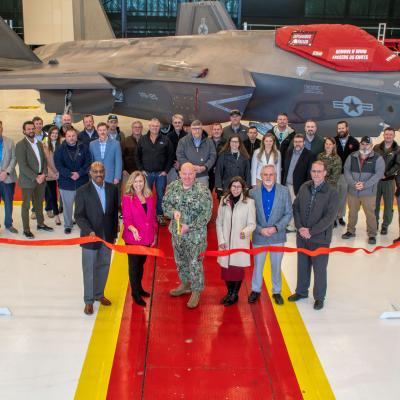 Group of people posing in front of F-35 aircraft during ribbon cutting 