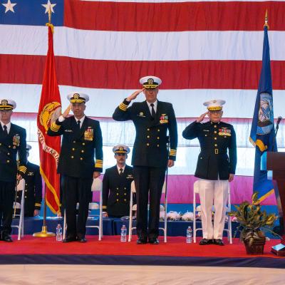 Sailors stand on a stage saluting