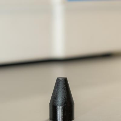 Close-up image of a small, black polymer cone that was 3D printed as a tool for F-35 Lightning II maintenance 