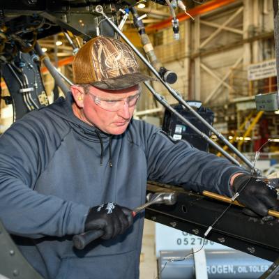 Man using hammer to work on metal aircraft frame