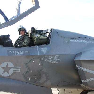 Pilot sits in F-35B Lightning II cockpit with canopy up.