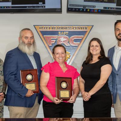 Group of five pose for photo with award plaques 