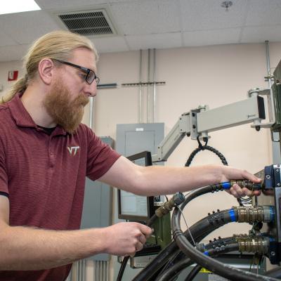 Man in red shirt plugging large cords into machine 