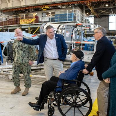 Four people standing and one person in wheelchair in aircraft hangar