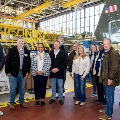 Group photo of people standing on red isle in an aircraft hangar