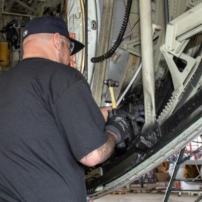 man in black shirt works on inside of aircraft