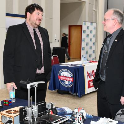 Two men talk in front of expo table
