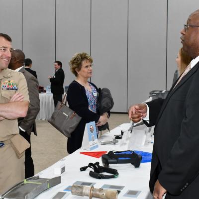 Two men speak across expo table