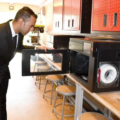 Engineer opens door of 3D printer in mobile lab trailer