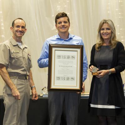 Shawn Higgins accepts the Dr. William B. McLean Memorial Award from Rear Adm. Scott Dillon, NAWCWD commander, and Joan Johnson, NAWCWD executive director, during the 2019 Honorary Awards Ceremony at China Lake on June 25. (U.S. Navy photo by Ryan Smith)