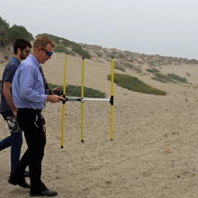 Diane Phung, Thomas Hentges, and Phillip Porter hunt for a transmitter hidden on the beach in Point Mugu, California, 