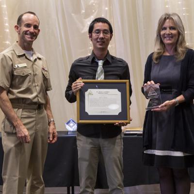 Alex Oshiro accepts the Dr. Twain C. Lockhart Memorial Award from Rear Adm. Scott Dillon, NAWCWD commander, and Joan Johnson, NAWCWD executive director, during the 2019 Honorary Awards Ceremony at China Lake on June 25. (U.S. Navy photo by Ryan Smith)