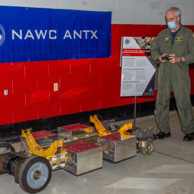 Naval Air Force Atlantic Commander, Rear Adm. John F. Meier, parks a mechanized weapons skid developed by the Naval Air Warfare Center Aircraft Division during its third annual Advanced Naval Technology Exercise at indoor site at Lakehurst, New Jersey..