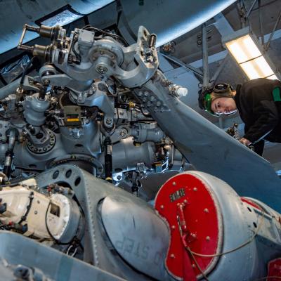A Sailor inspects rotor gear for corrosion aboard the MH-60S Seahawk Helicopter.