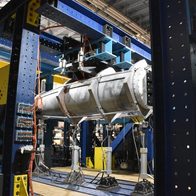 A metal fuel pod is mounted onto test equipment in a laboratory.
