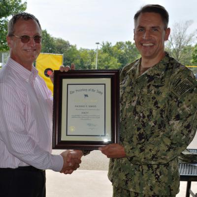 Zach Simons, left, receives a plaque Aug. 16 from Rear Adm. Mike Zarkowski