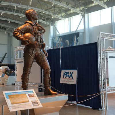 A bronze statue of a test pilot stands before a museum exhibit curtained off from visitors while under construction.