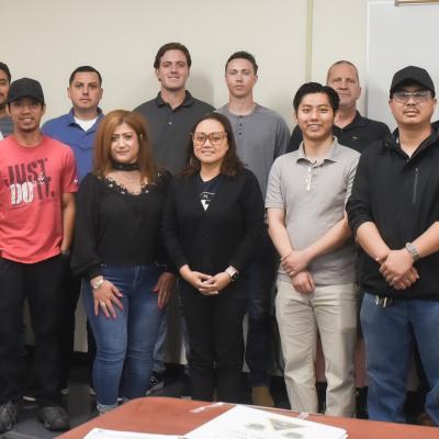 A group of new hired personnel standing and smiling in front of the camera. 