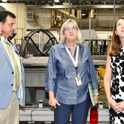 Group of two women and one man look at ceiling in aircraft hangar