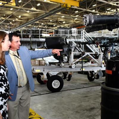 Man points at H-53 rotor head while talking with woman