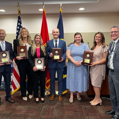 pictured: NAVAIR award-winners: (left to right) Jason Tiede,  Tess Butner, Mandy Miedzinski, Tyler Vallandingham,  Shelbee Mattingly, Kari O’Brien,  Pat Lowien, NAVAIR comptroller 