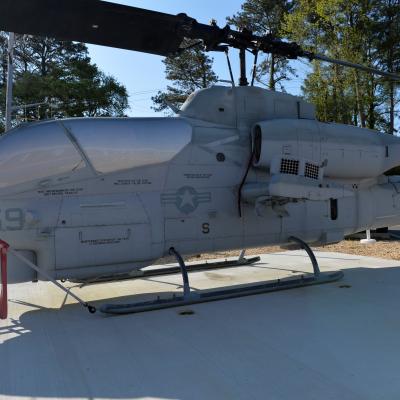 An AH-1W Cobra is displayed in front of an aircraft hangar.