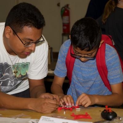 Kenn Hernandez, an electrical engineer at Naval Air Warfare Center Weapons Division, helps a student build a drone during a four-day coding camp in Ridgecrest, California on June 3-6. (U.S. Navy photo by Paul Kakert)