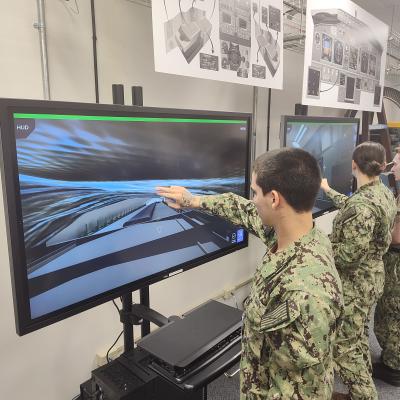 Three sailors in uniform training on virtual touch-screens