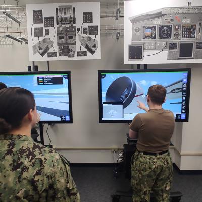 Three sailors in uniform conducting training on virtual touch-screens