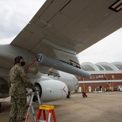 A member of VX-20 puts a radio frequency countermeasure on a P-8A Poseidon.