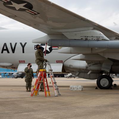 A member of VX-20 puts a radio frequency countermeasure on a P-8A Poseidon. 