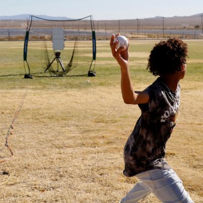 A Burroughs High School student winds up to throw a pitch so that the radar can measure its speed during the BHS STEM day Nov. 8. (U.S. Navy photo by Paul Kakert)