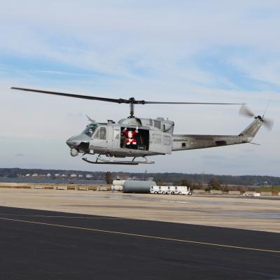 Adm. Claus waves from a helicopter near the Patuxent River in a red specialty flight suit.