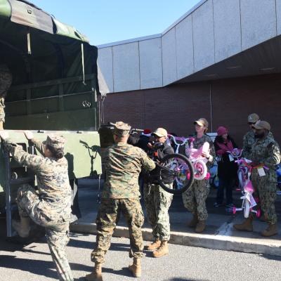 Volunteers work with Sailors from Joint Base McGuire Dix Lakehurst to fill trucks with toys for the annual Toys for Tots drive.