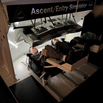 Two Navy pilots operate an Orion spacecraft display monitor.