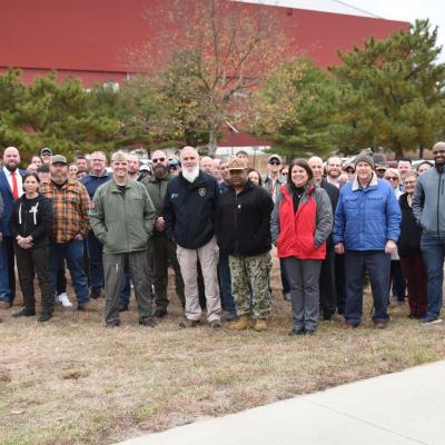 Team members from Naval Air Warfare Center Aircraft Division Lakehurst attend a tree dedication ceremony