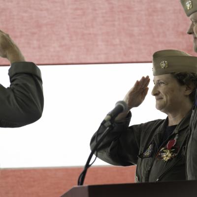 Rear Adm. Evans salutes Capt. Somerville in front of a flag at the podium during the Naval Test Wing Atlantic change of command.