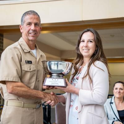 PMA-276’s Sharon Shaw accepts the 2022 NAVAIR Commander’s Award in the ‘Workforce Development’ category from Vice Adm. Carl Chebi, commander, NAVAIR, on behalf of the Light Attack Academy team. 