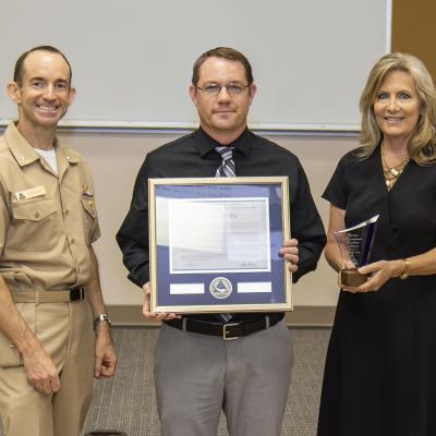 Rear Adm. Scott Dillon, left, NAWCWD commander, and Joan Johnson, right, NAWCWD executive director, pose with Business Management Excellence Award winner Bretton West during the Honorary Awards Ceremony in Point Mugu, California, on June 27. (U.S. Navy photo by Rob Grabendike)