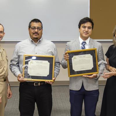 Rear Adm. Scott Dillon, left, NAWCWD commander, and Joan Johnson, right, NAWCWD executive director, pose with Dr. Twain C. Lockhart Memorial Award winners Michael Arroyo and Tyler Halpin-Chan during the Honorary Awards Ceremony in Point Mugu, California, on June 27. (U.S. Navy photo by Rob Grabendike)