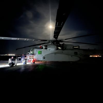 Helicopter sits on a dark runway with the moon shining overhead