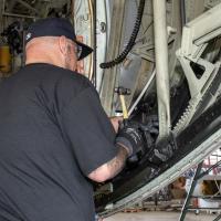 man in black shirt works on inside of aircraft