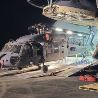 HH-60W helicopter coming out of a C-5 aircraft nose at night 